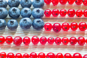 Patriotic American flag cake with blueberries and red currant on vintage wooden background